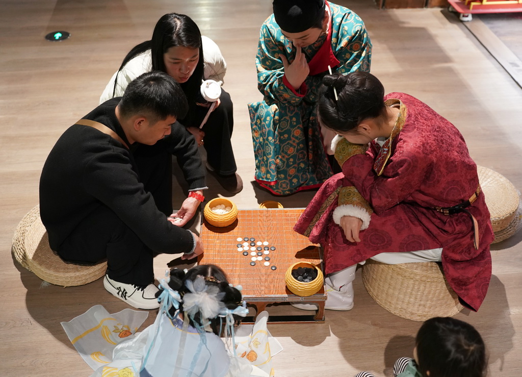 12月23日，游客与街区工作人员扮演的角色对弈。