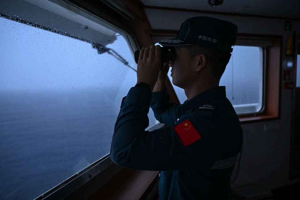 11月22日日出前，在巡航值守于中国南海黄岩岛海域的黄岩舰上，海警执法员在驾驶室查看周边海域情况。