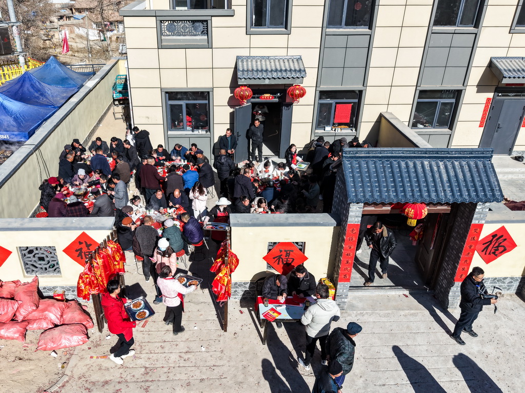 12月29日，村民在榆中县马坡乡马莲滩村集中安置点的新家里举办乔迁宴（无人机照片）。