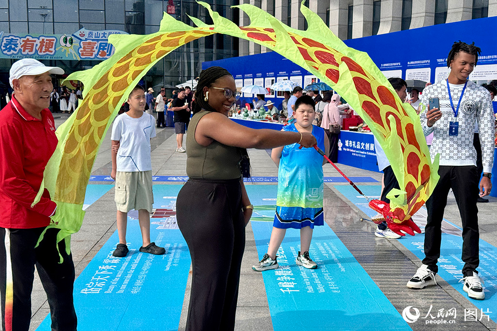2025年9月7日,在第三十九届泰山国际登山节活动现场,外国友人体验舞龙彩带,感受中华文化的独特魅力。人民网 郑昕桥摄