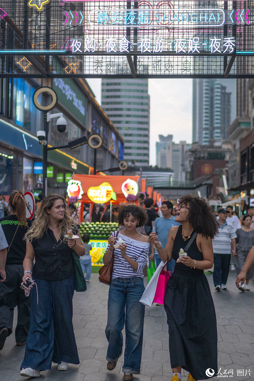 2025年10月2日,在上海吴江路夜市,外国游客品尝特色美食。人民网记者 翁奇羽摄