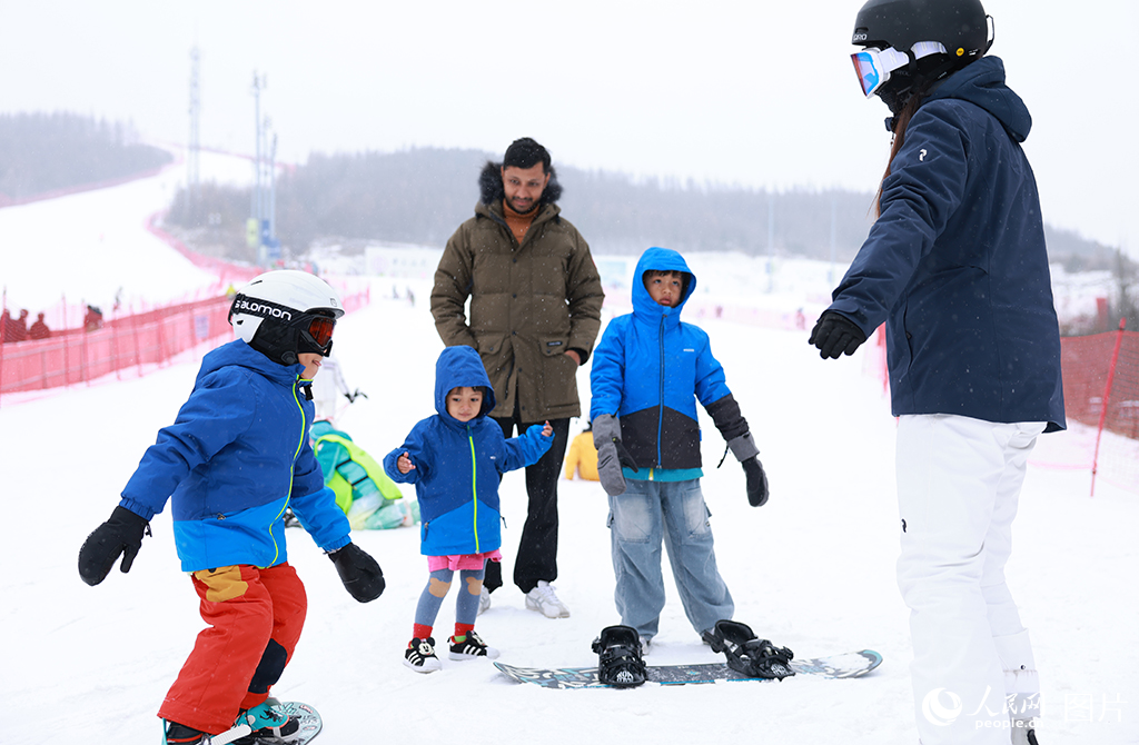 2025年12月12日,在河北崇礼翠云山银河滑雪场,教练正教来自美国的San一家滑雪。人民网记者 李兆民摄