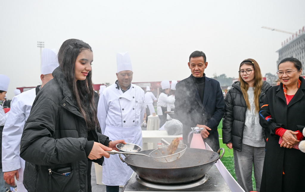 12月30日，外国游客在厨师指导下体验“璧山来凤鱼”的制作过程。