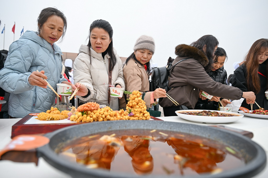 12月30日，当地市民在比赛现场品尝特色美食。