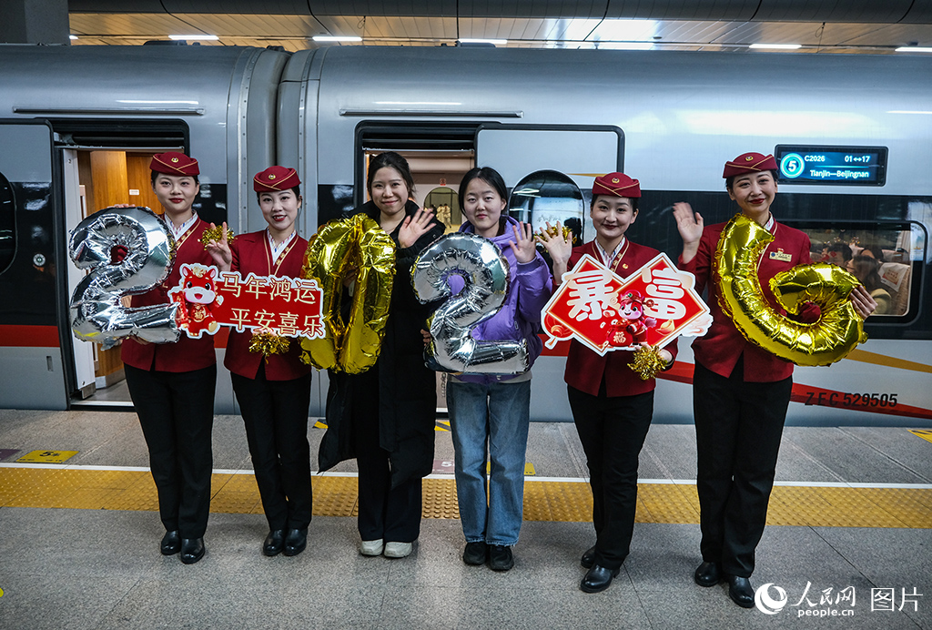 12月30日，C2026次列车乘务人员与旅客在站台合影留念。
