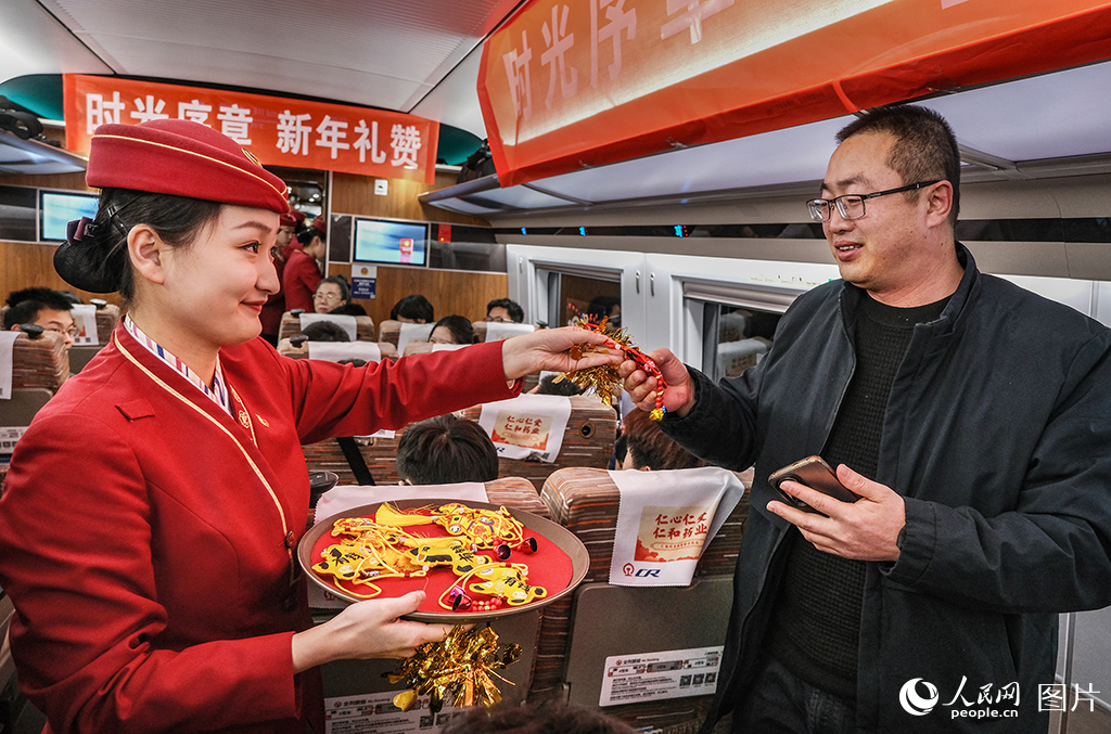 12月30日，C2026次列车上乘务人员为旅客送上迎新年纪念礼品。