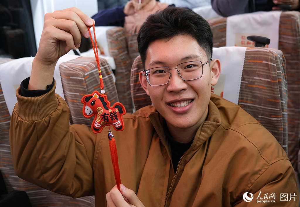 12月30日，C2026次列车上旅客展示新年纪念礼品。