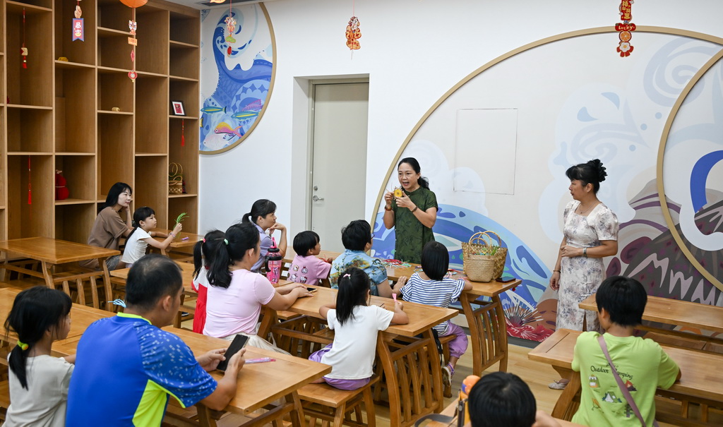 2025年10月12日，在海南省文化馆，东山草编技艺传承人袁洁（后中）为家长和小朋友们讲解东山草编技艺。新华社记者 杨冠宇 摄