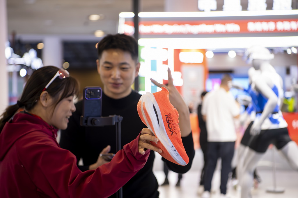 1月8日，两名体育用品企业工作人员在博览会现场利用电商平台直播推销运动鞋。