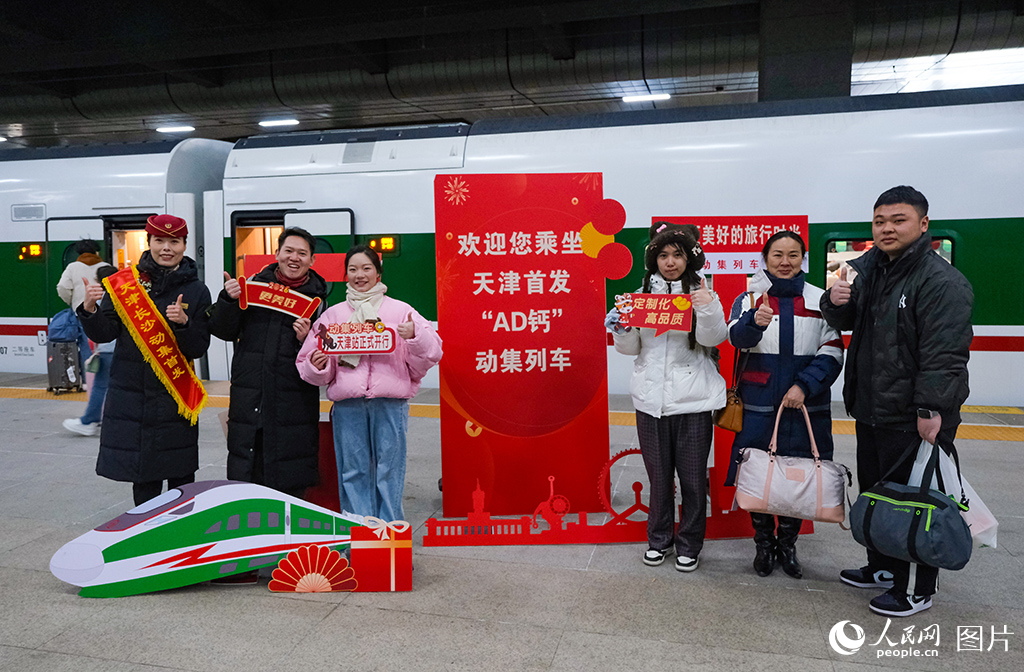 1月19日，天津首趟开出天津至长沙动力集中型动车组列车乘务人员与旅客在站台合影留念。杨宝森摄