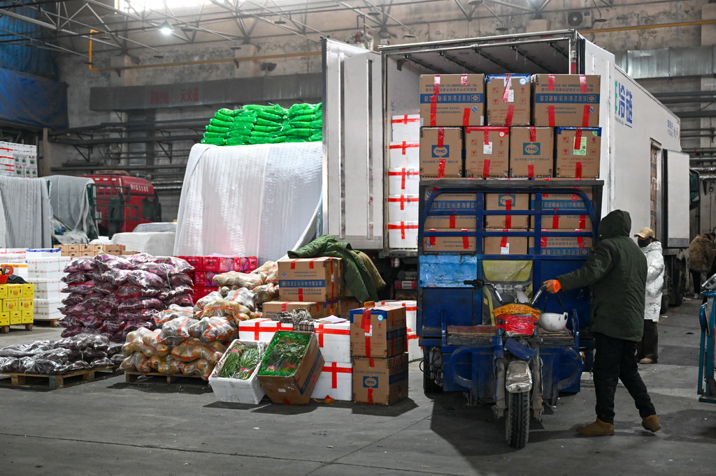 在新疆乌鲁木齐市九鼎农产品批发市场蔬菜交易中心,商户接车准备卸菜(1月19日摄)。