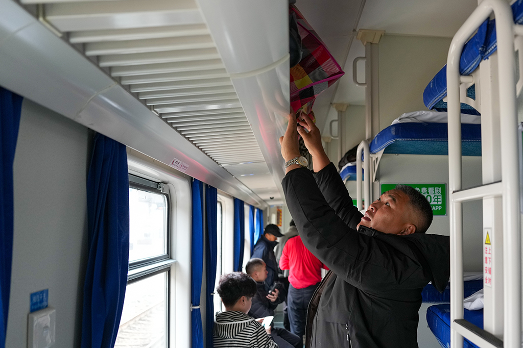 1月25日,在广州火车站,旅客在K303次列车上摆放行李。