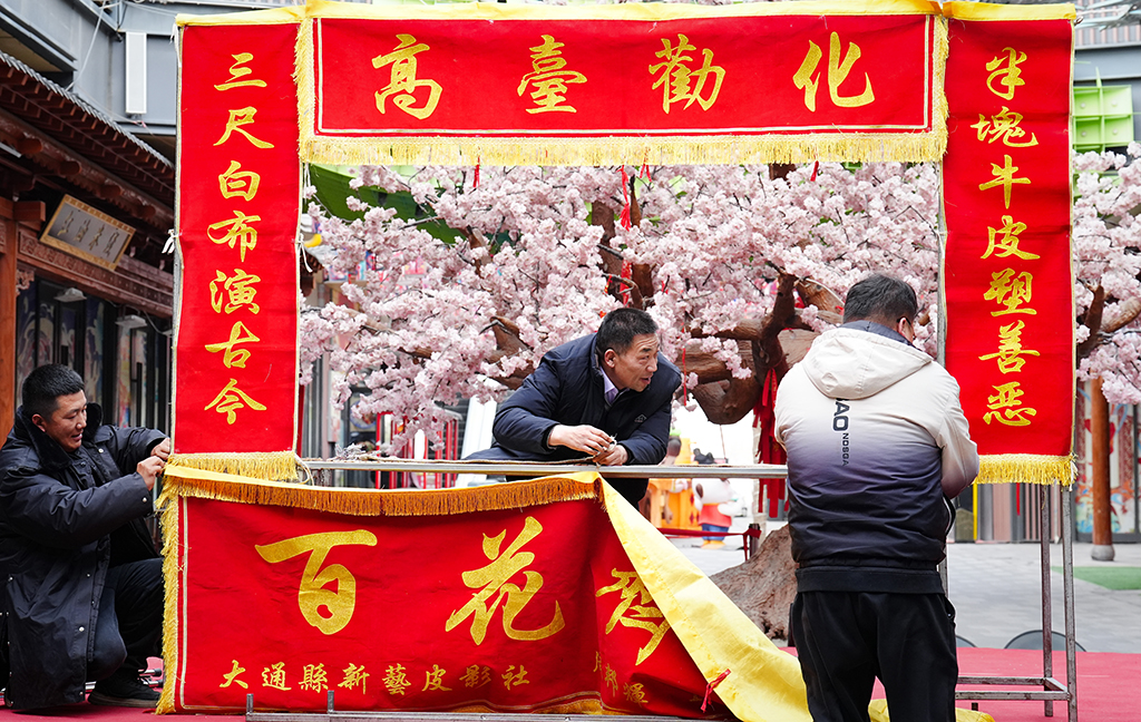 1月25日,在青海省西宁市城北区,周邦辉(中)与徒弟刘成玉(左)、儿子周德鹏搭建皮影戏台。