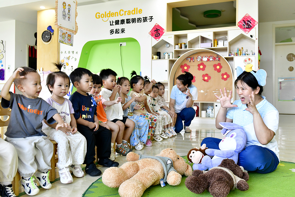 2025年7月22日,在山东省滨州市博兴县金色摇篮幼儿园,老师带托育班的孩子做游戏。新华社记者 郭绪雷 摄