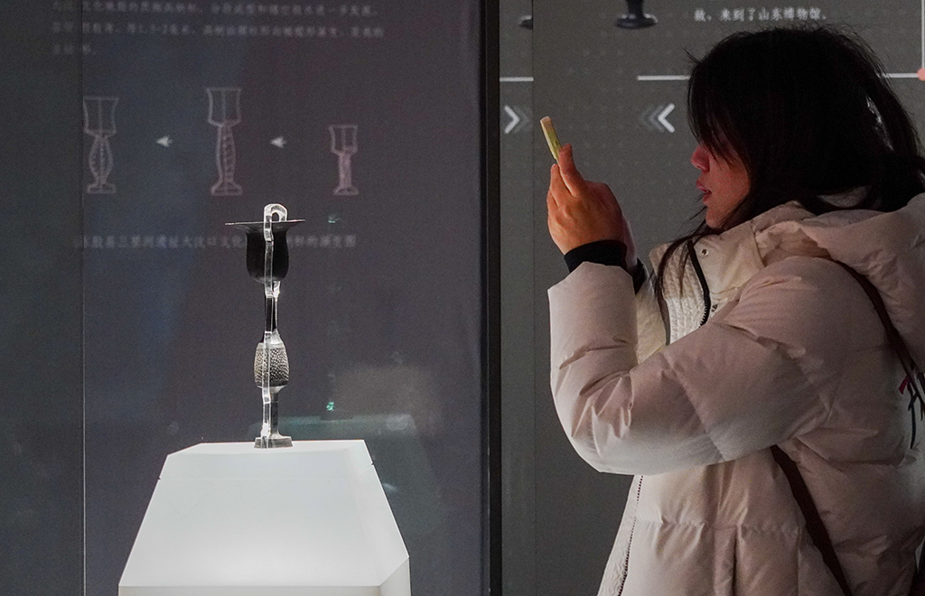 1月27日，在山东博物馆“对话蛋壳黑陶高柄杯”明星文物展上，一名参观者观看龙山文化蛋壳黑陶高柄杯。新华社记者 徐速绘 摄