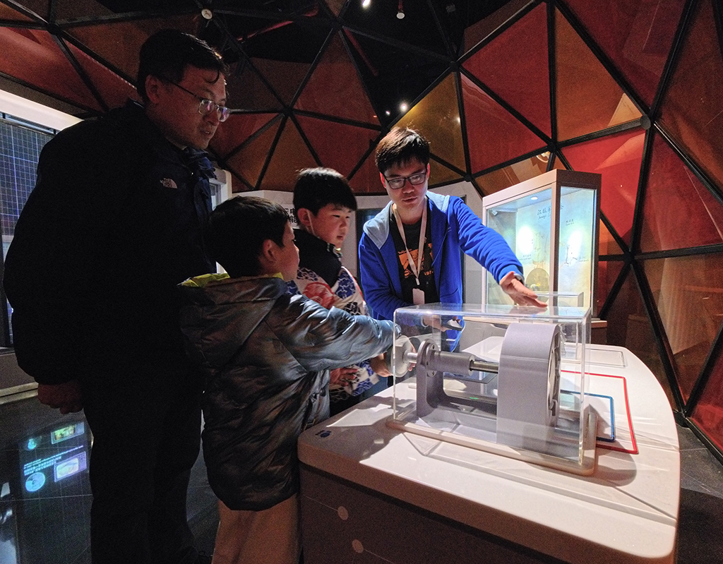 1月27日，工作人员（右一）指导参观者进行科学游戏体验。