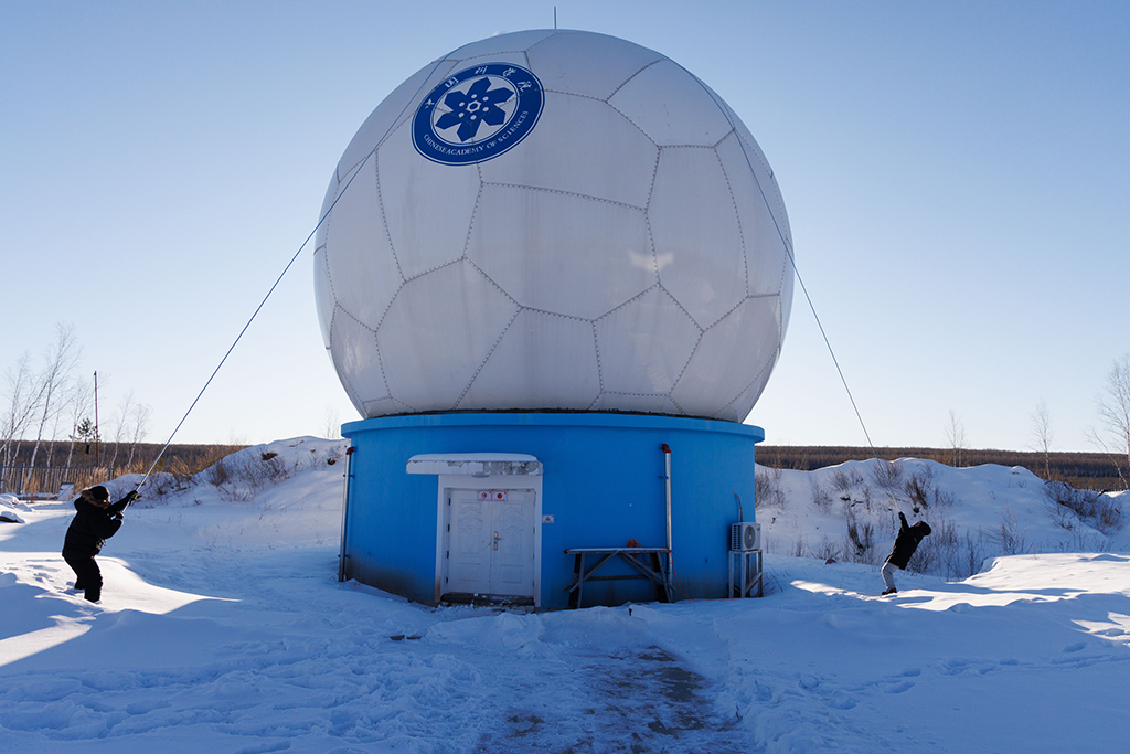 1月25日，工作人员李强（左）和田冬在一起清除天线罩顶上积雪。