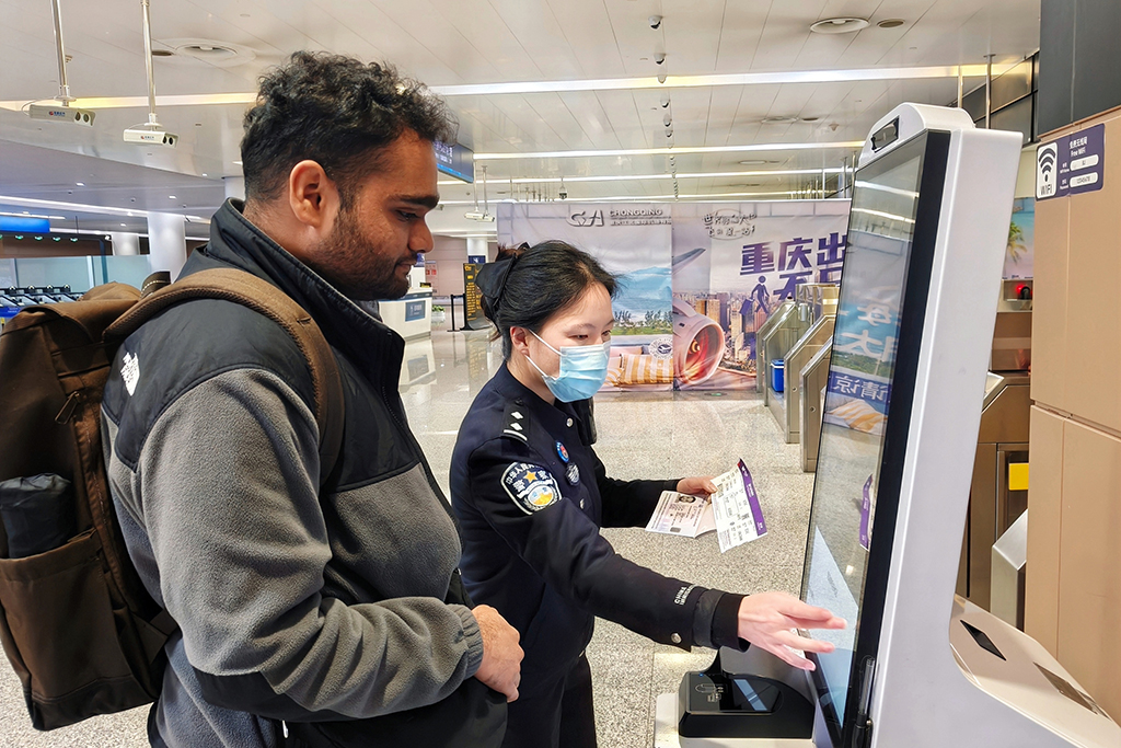 在重庆江北国际机场，重庆出入境边防检查总站民警帮助入境的新加坡旅客填写入境信息（1月7日摄）。