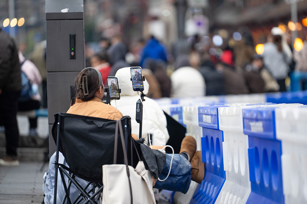 1月21日，在重庆市网红地标洪崖洞，主播在滨江路人行道上架设设备直播。新华社记者 唐奕 摄