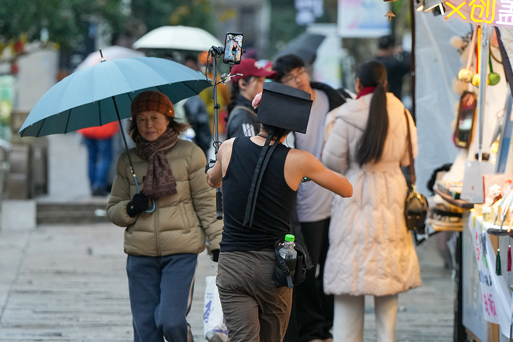 1月26日，在苏州市平江路，一名主播手持直播设备、便携音响边走边唱，进行“游街式”直播。新华社发