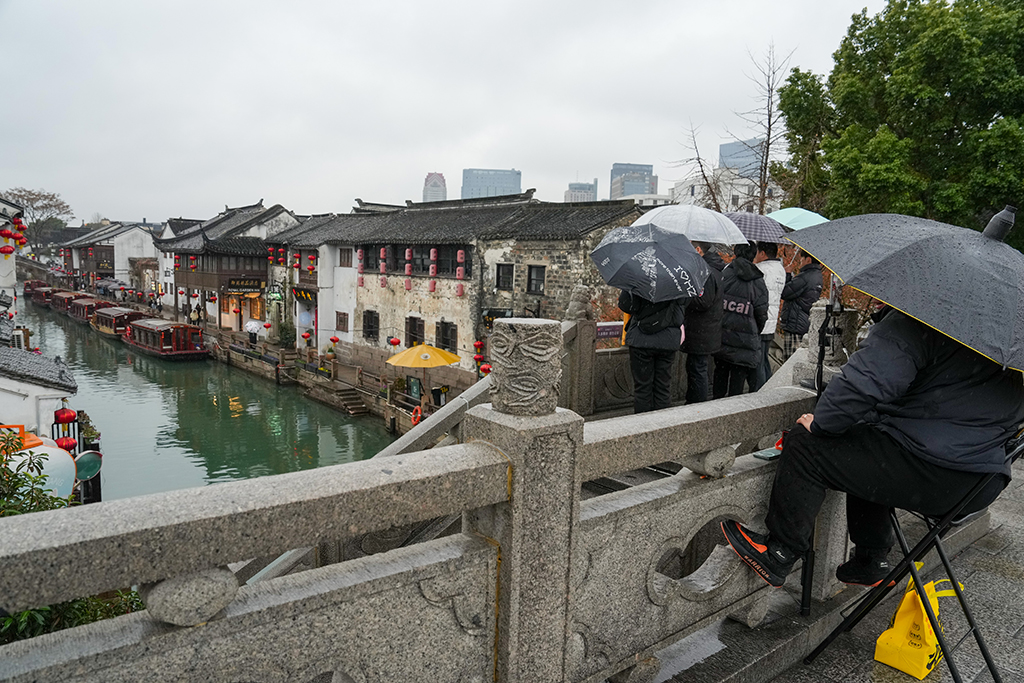 1月26日，在苏州市山塘街，一名主播（右一）携带折叠椅、直播器材长期占道直播。 新华社发