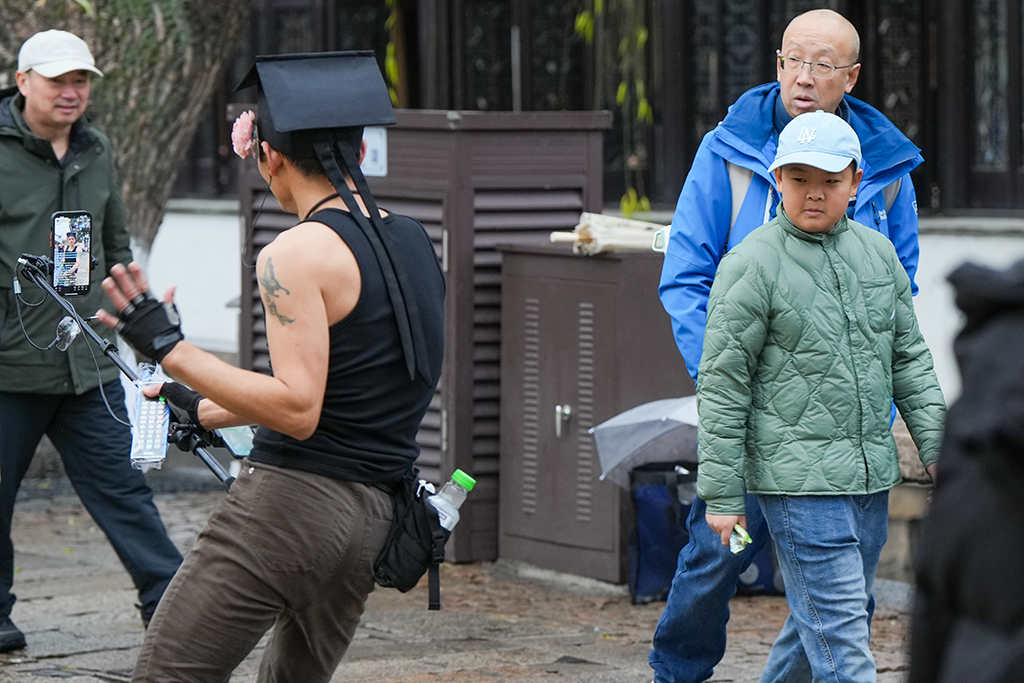 1月26日，在苏州市平江路，一名主播手持直播设备、便携音响边走边唱，“游街式”直播的喧闹声响吸引行人侧目。新华社发