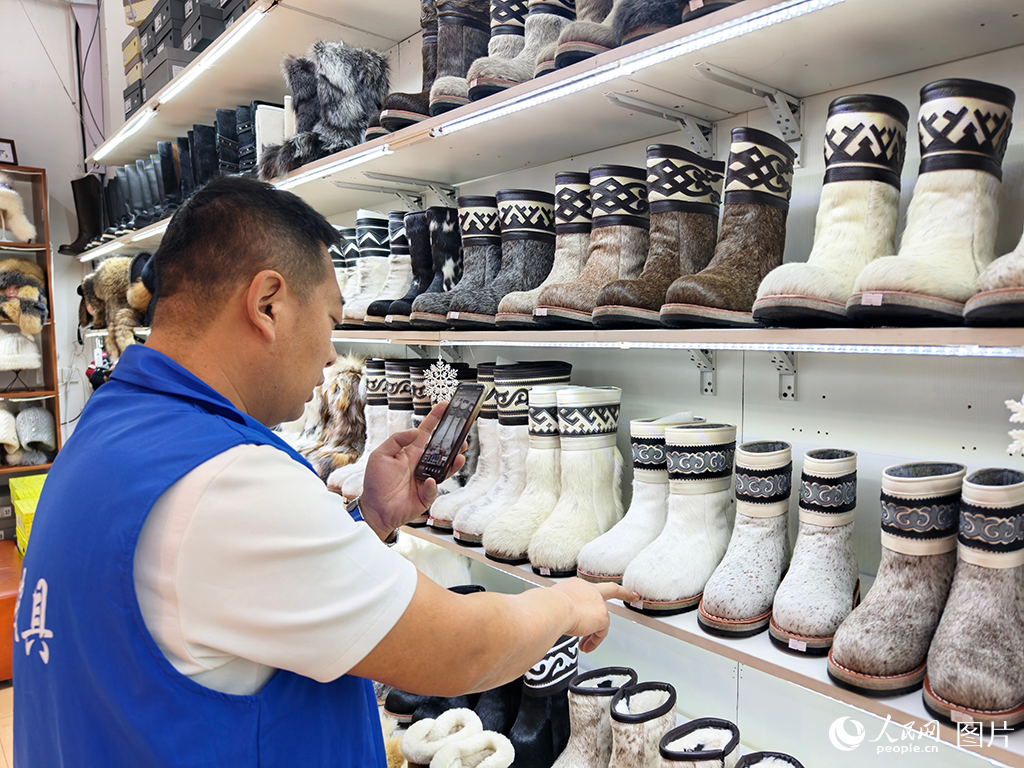2025年12月22日，在内蒙古呼伦贝尔市的一家鞋店内，店员正在线上帮助顾客选购马毛靴。人民网记者 赵梦月摄