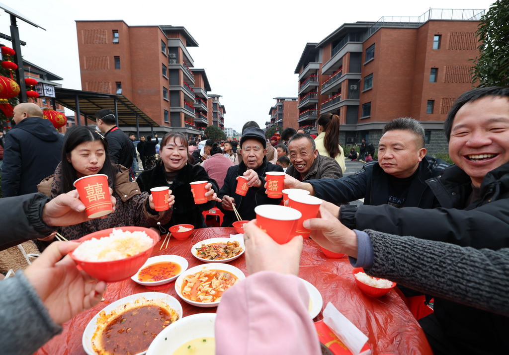 1月31日，在四川省宜宾市筠连县沐爱镇金坪村搬迁安置区，受灾群众在百家宴上举杯相互祝福。
