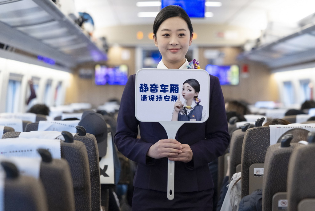 2月1日，铁路上海客运段乘务员在G12次列车车厢内手举静音车厢提示牌。新华社记者 王翔 摄