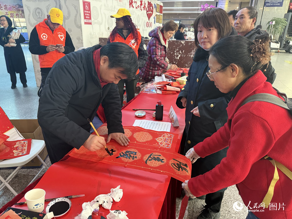 2月2日春运第一天，在武昌火车站，书法爱好者为春运回家旅客写春联。人民网记者 张沛摄