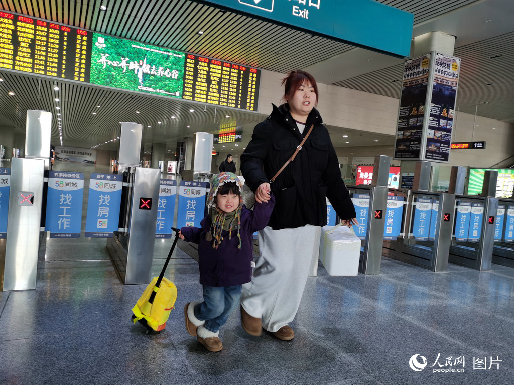 2月2日，在长春西站，现住大连的于女士一家三口回长春娘家探亲，孩子的笑容温暖了站台。人民网记者 王帝元摄