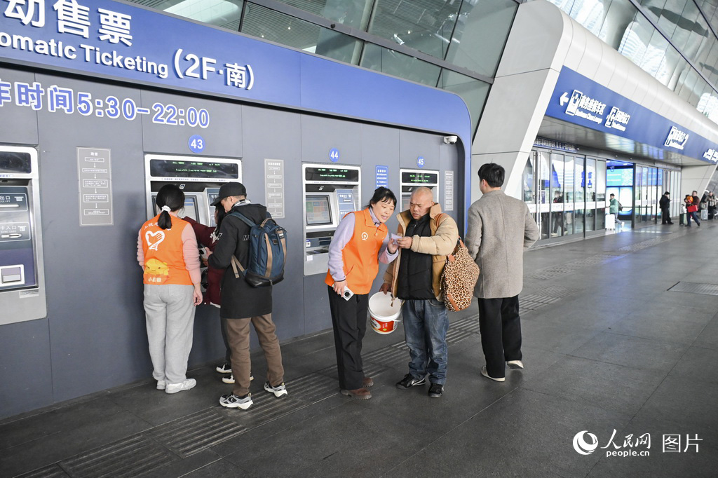2月1日，杭州东站自动售票机前，志愿者为旅客提供帮助。人民网记者 叶宾得摄