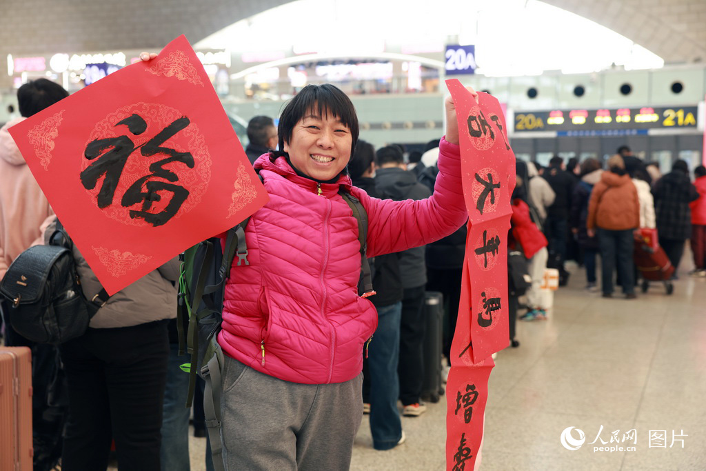 2月2日，河北石家庄站书法公益活动现场，旅客收到福字和春联后开心的向记者展示。人民网记者 李兆民摄