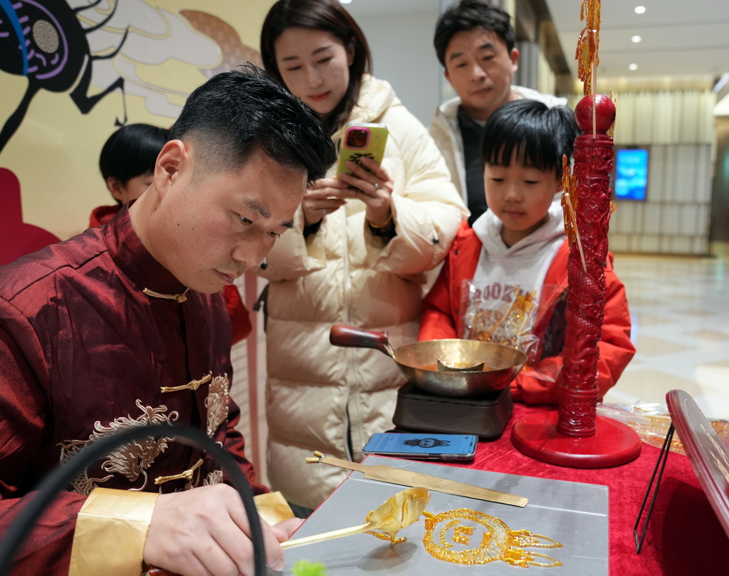 2月1日晚，在BFC外滩金融中心商场，手工艺人制作玩偶糖画。