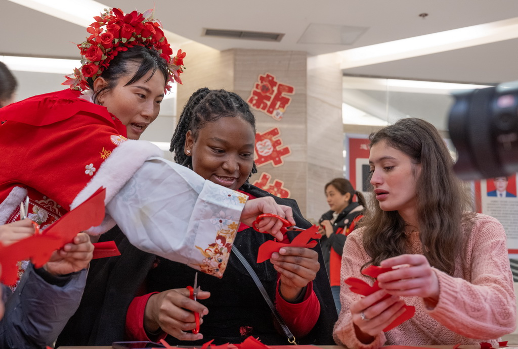 2月3日，在重庆市巴南区，留学生在老师的指导下体验剪纸。