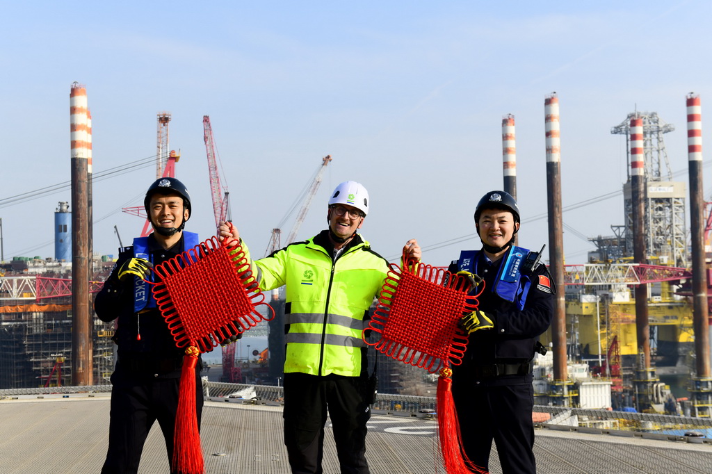2月3日，在中集来福士山东烟台建造基地，山东出入境边防检查总站烟台边检站来福士警务室的民警赠送比利时风电安装船船长中国结，并合影留念。