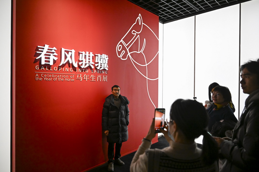2月4日，观众在“春风骐骥：马年生肖展”展板前拍照留念。