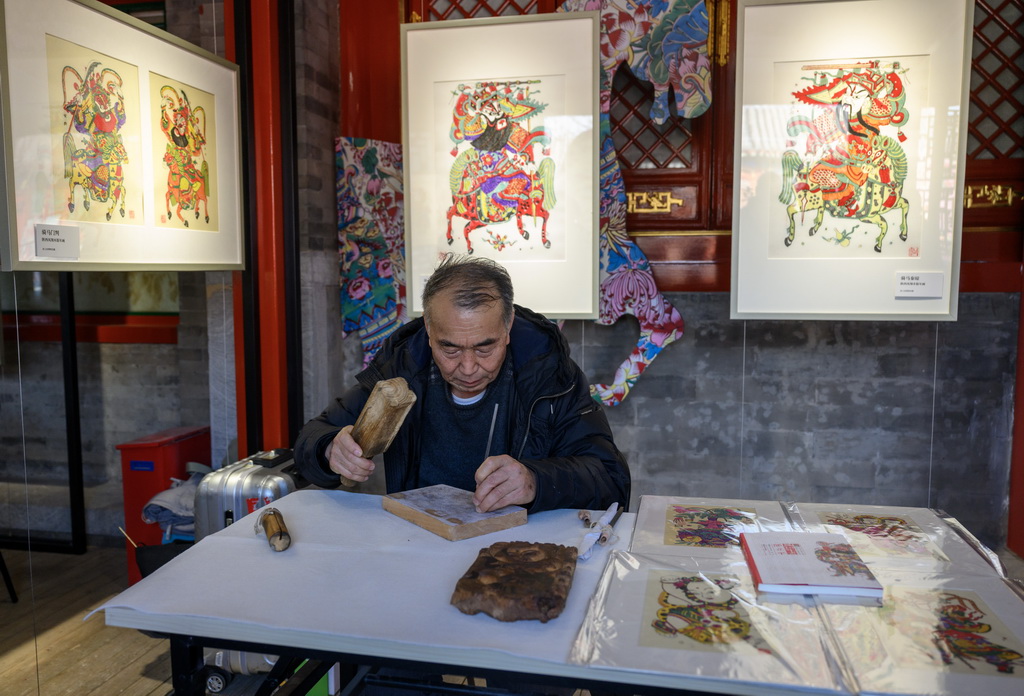 2月4日,国家级非物质文化遗产项目凤翔木版年画代表性传承人邰立平在展览现场雕版。