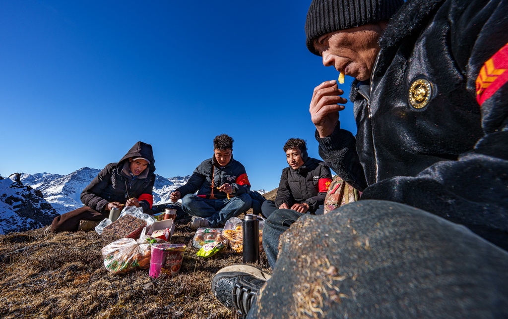2月6日,在西藏山南市隆子县玉麦乡境内,护边员们在巡逻途中吃午饭。他们围坐在一片平坦草地,从背包里掏出糌粑、卡塞(一种传统油炸面食),再喝几口酥油茶,这就是巡逻护边途中一顿简单的午餐。