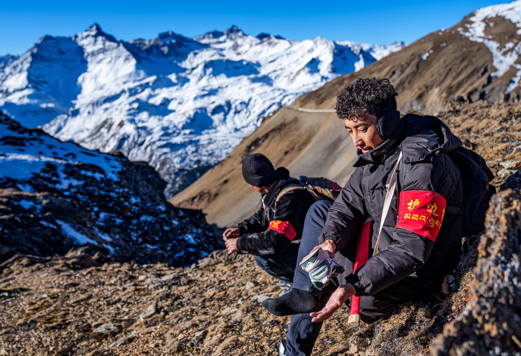 在西藏山南市隆子县玉麦乡境内,护边员拉巴次仁(右)在清理灌进鞋里的沙石和积雪(2月6日摄)。