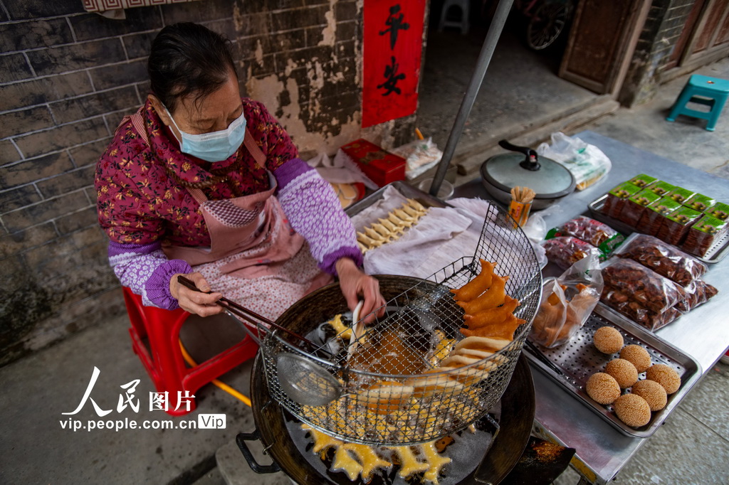 2026年2月5日，广西靖西市新靖镇旧州街小摊点业主在制作油炸“哞咩”“番叽嘟”等特色小吃。