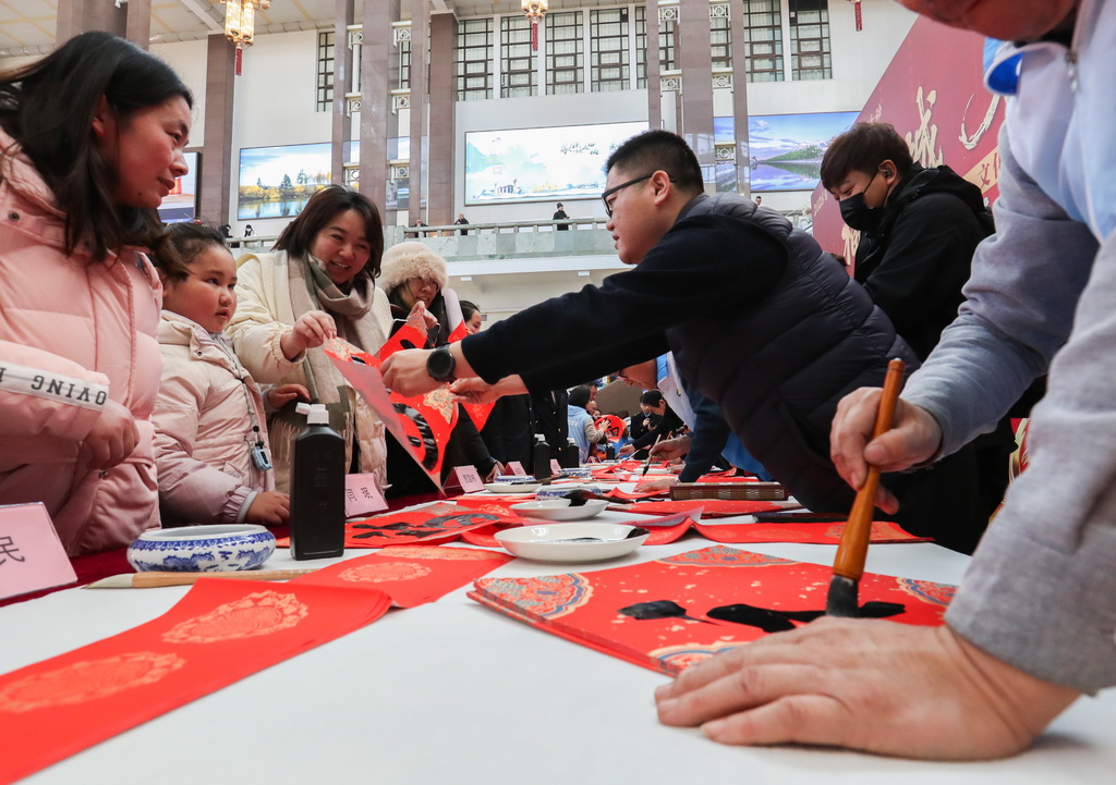2月10日，文化志愿者在现场为旅客书写“福”字。
