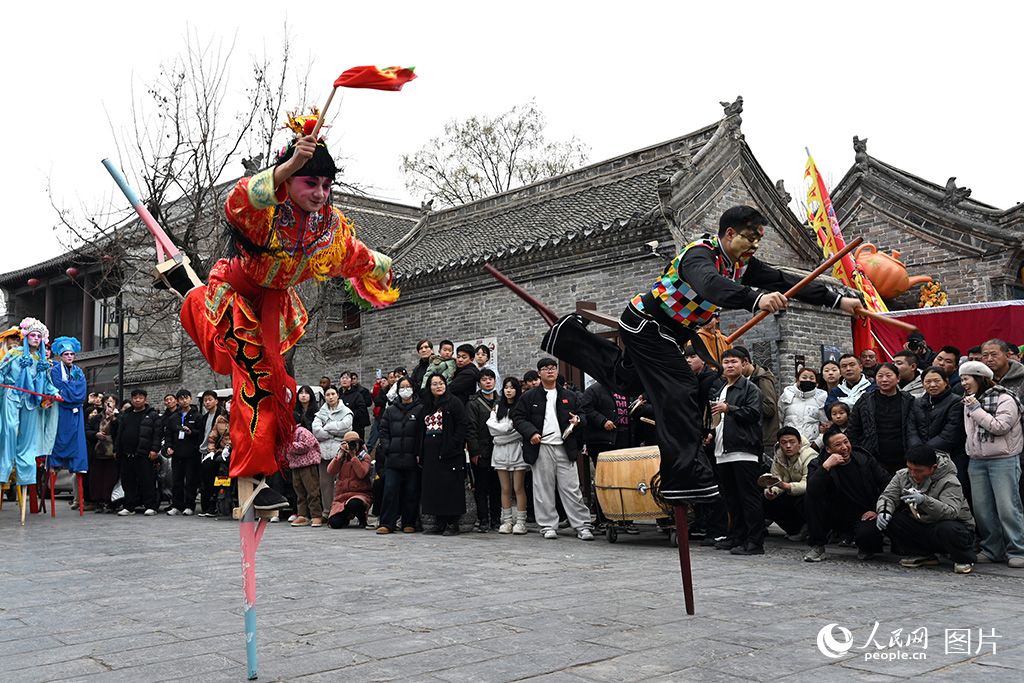 2026年2月10日北方小年，“春满中原·老家河南”主题活动豫北主会场在安阳市滑县启动，游客在道口古镇观看高跷表演。人民网记者 王玉兴摄