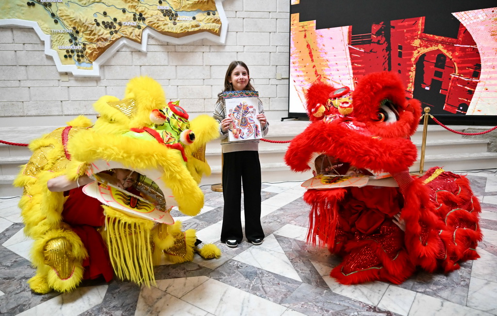 2月23日，在位于阿拉木图的哈萨克斯坦中央国家博物馆，一名女孩在开幕式后与舞狮合影。