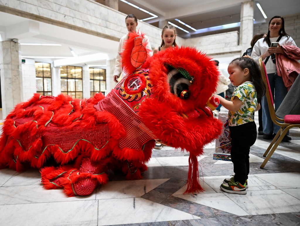 2月23日，在位于阿拉木图的哈萨克斯坦中央国家博物馆，一名女孩在开幕式后与舞狮互动。