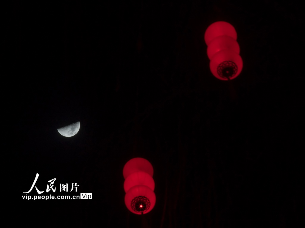 2026年2月24日，在山西省武乡县，新春彩灯映衬下的上弦月格外亮眼。李勇摄（人民图片网）