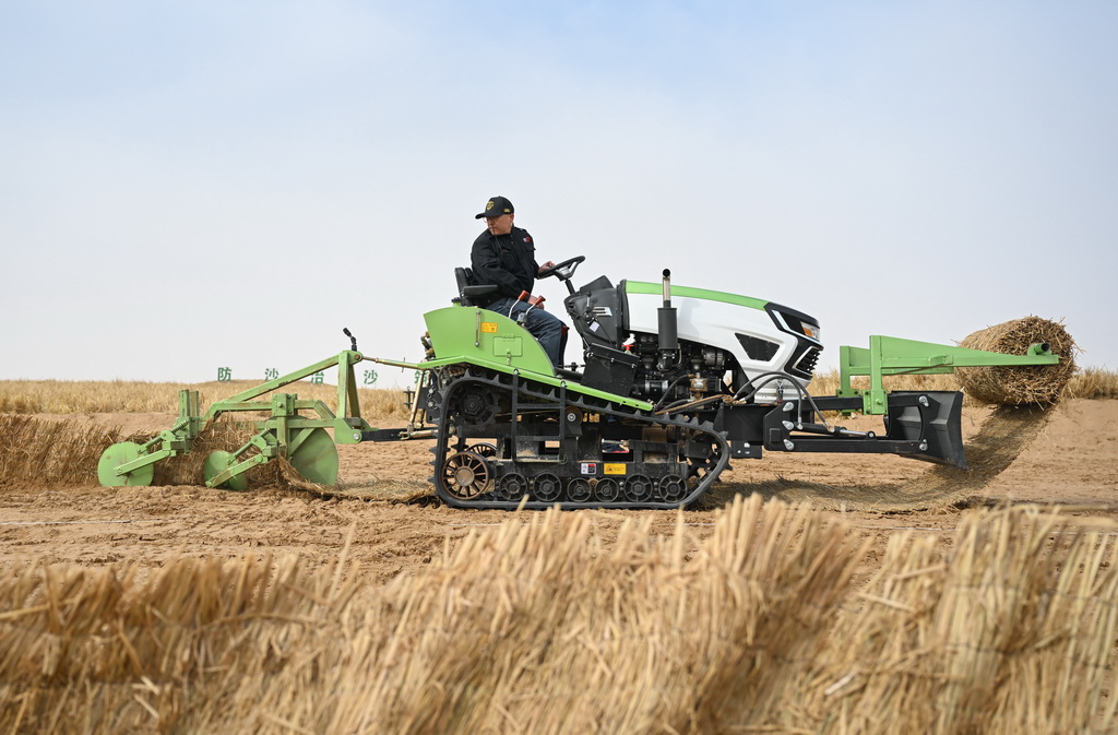 2月28日,工人在内蒙古阿拉善盟境内的乌兰布和沙漠驾驶小型履带沙障机作业。