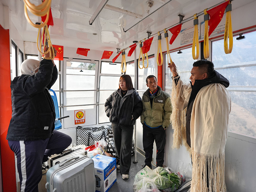 1月28日,郑望春在古路村索道车厢内和外出务工返乡的村民交流。
