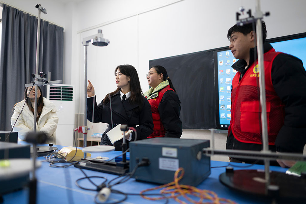 2月4日,在湖北民族大学,张琼丽(左二)与物理系科技志愿服务队队员交谈。张琼丽和湖北民族大学物理系科技志愿服务队合作,面向大中小学师生,积极开展“科普+思政”活动。