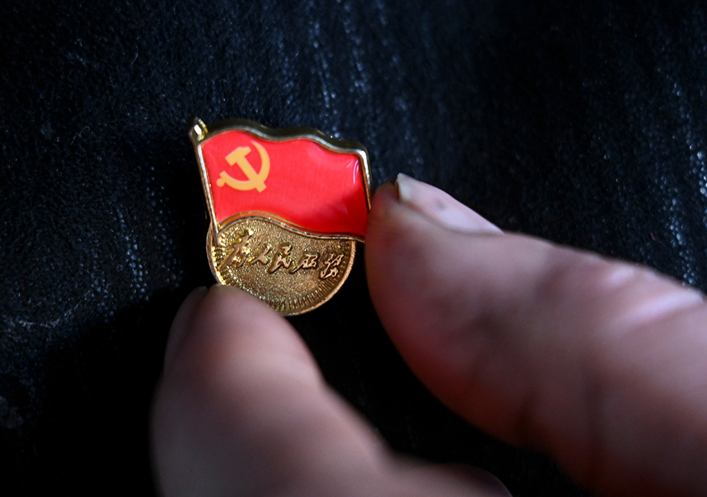 2月9日,在伊犁哈萨克自治州新源县,木沙江·海拉特在家中佩戴党徽准备出门。他要去克热格塔斯村党群服务中心听取群众的意见建议。新华社记者 王菲 摄